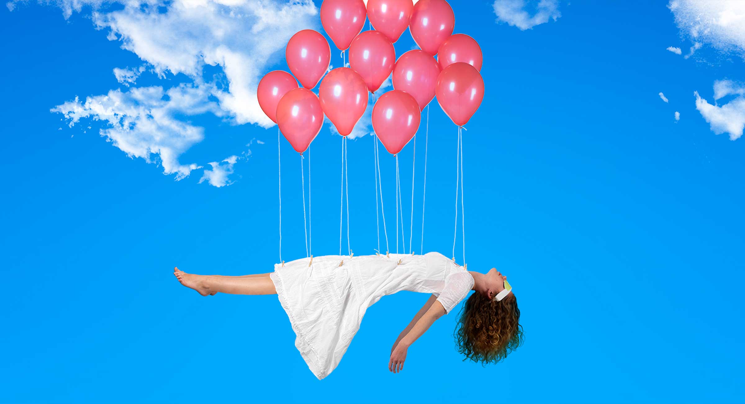 Woman in the sky, flying with a cloud of balloons